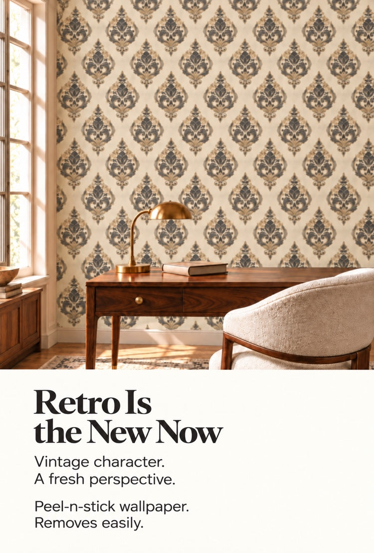 Vintage damask peel-and-stick wallpaper behind a wooden desk with a brass lamp and armchair